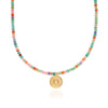 Necklace with multicolored beads and a gold pendant by Anna beck on a white background