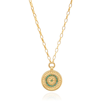 Gold necklace with a circular pendant featuring green stones on a white background
