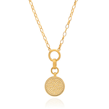 A gold chain necklace featuring a round, textured pavé-style disc pendant suspended from a ring clasp, shown on a clean white background with a subtle reflection.