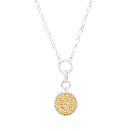 A silver chain necklace with a circular pendant featuring a textured gold center and a silver border, displayed on a clean white background.