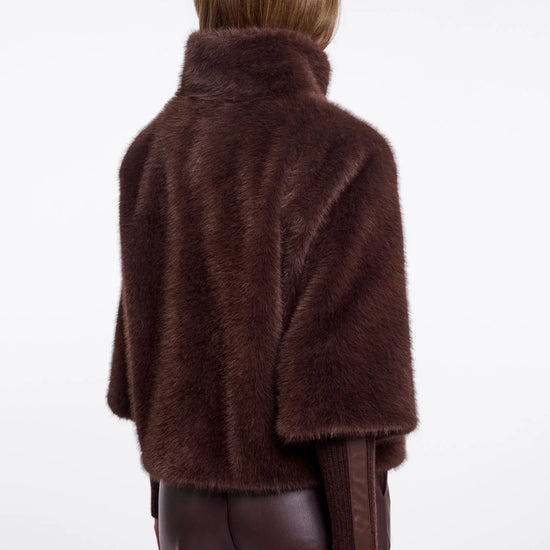 A model shown from the back wearing a dark brown faux fur cape jacket over a matching brown top and dark brown pants, set against a plain white studio background.