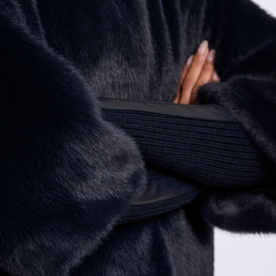 Close-up of a person wearing a dark fur coat with a blurred background