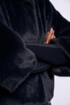 Close-up of a person wearing a dark fur coat with a blurred background