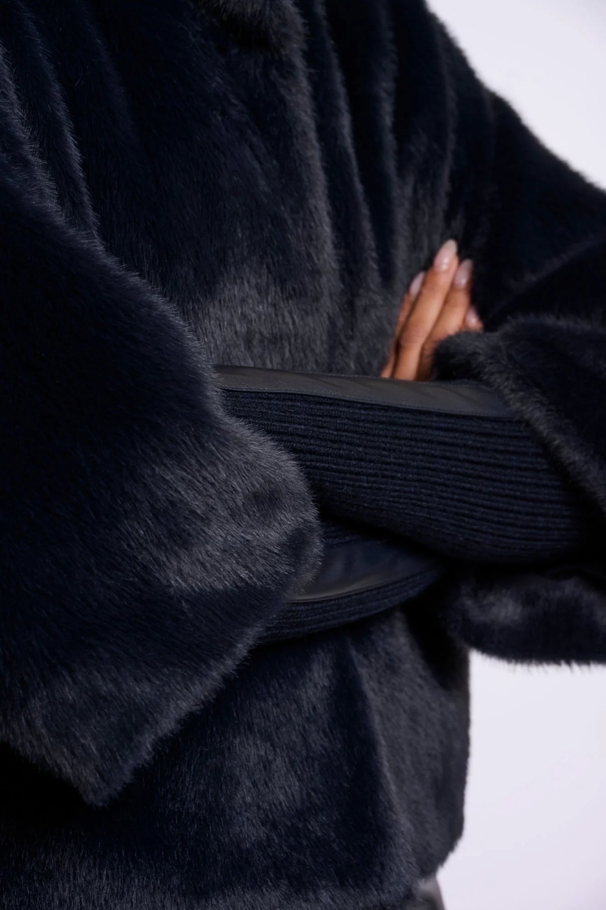 Close-up of a person wearing a dark fur coat with a blurred background