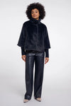Woman wearing a dark blue textured jacket and black leather pants on a white background