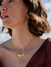 Woman wearing a gold necklace with a blurred natural background
