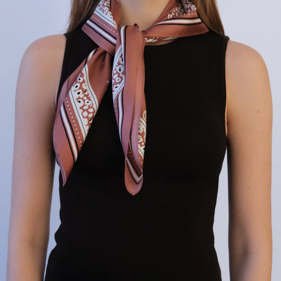 Person wearing a patterned scarf around their neck against a plain background