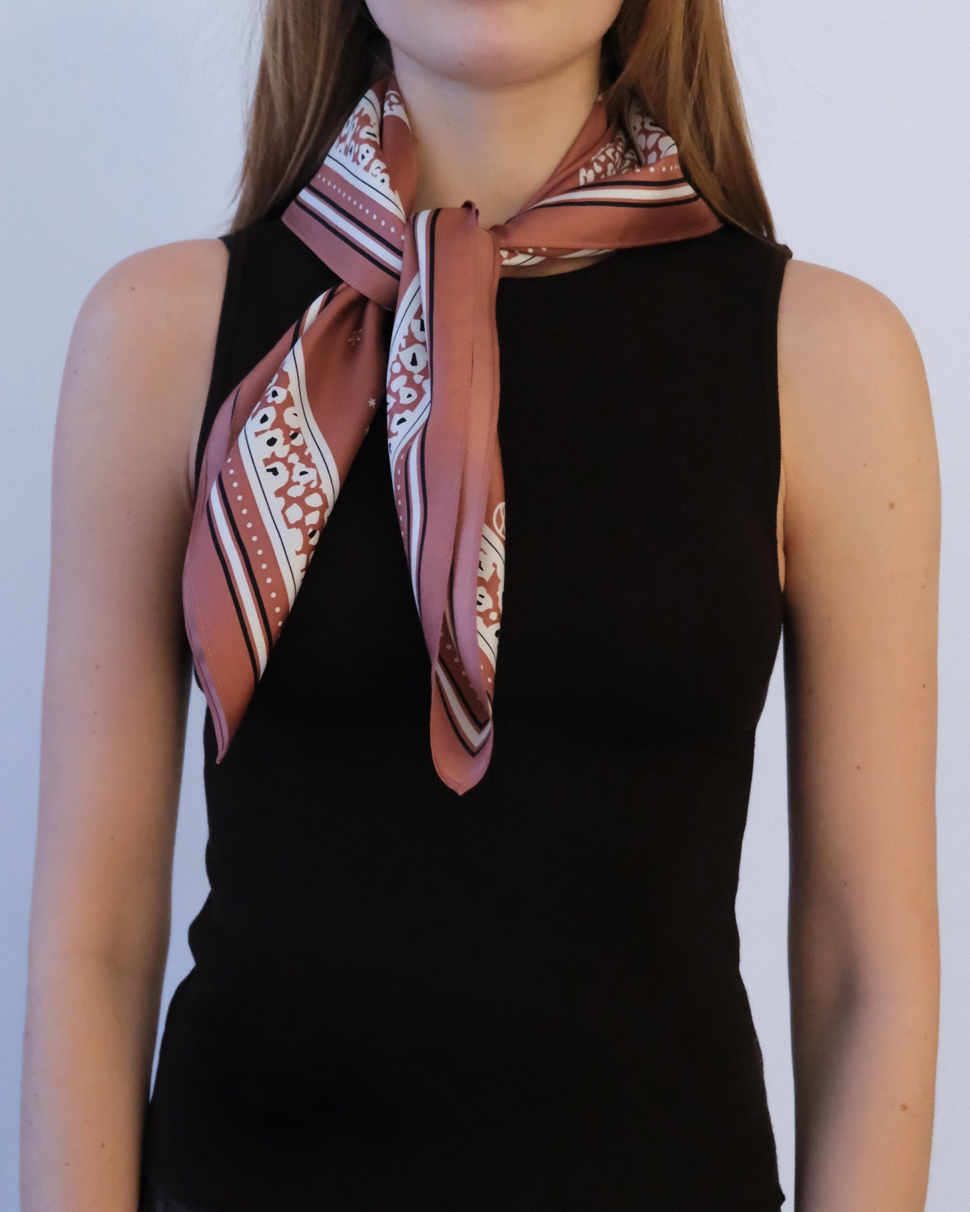Person wearing a patterned scarf around their neck against a plain background