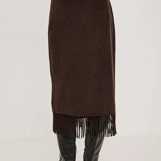 model wearing a brown skirt with fringe detail on the hem facing away from the camera 