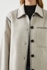 Light grey felt single breasted jacket with black chain stitching along the seams and edges with a patch pocket and brown tortoiseshell large buttons