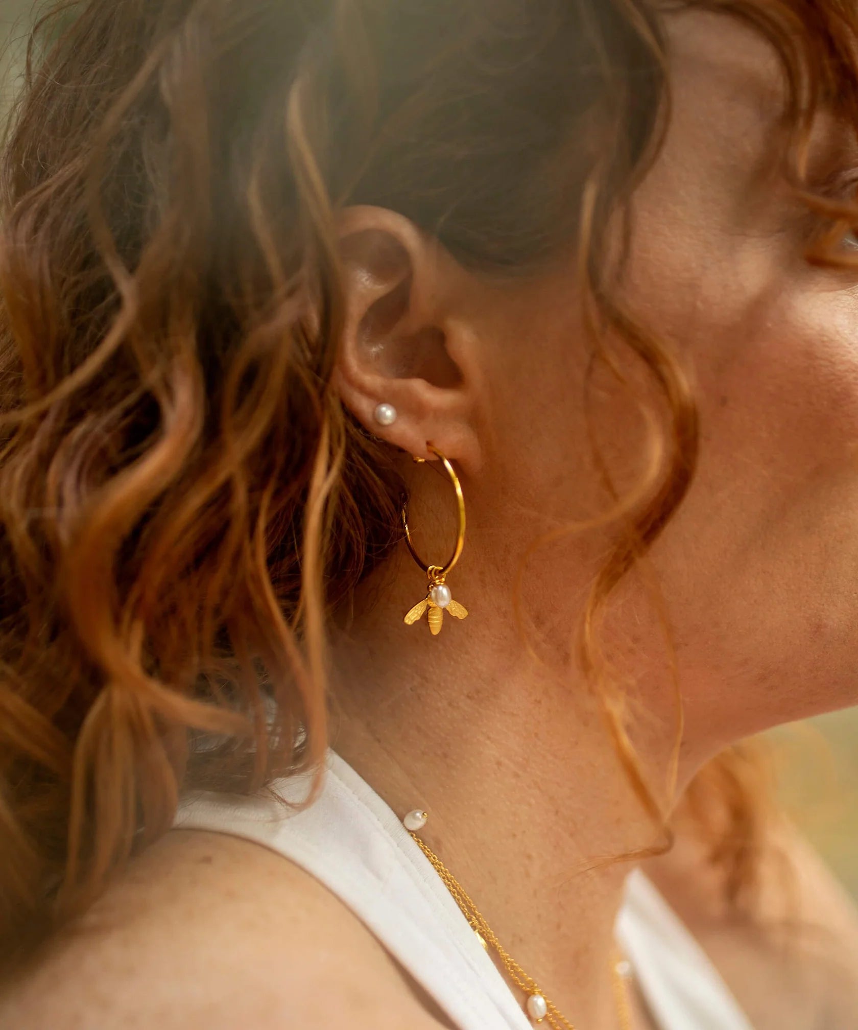 Large gold hoop earrings with flying bee pendants and a rice pearl drop with butterfly earring fastenings