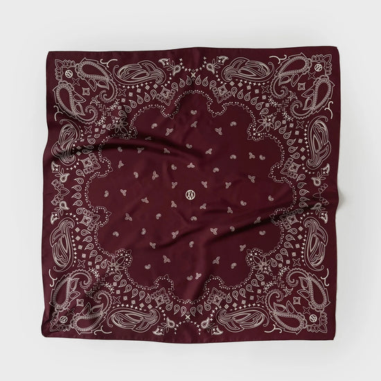 A square bandana in deep burgundy with a detailed paisley pattern in light gray, laid flat on a light gray background.