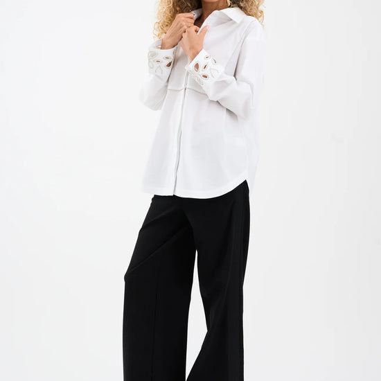 Woman wearing a white blouse and black pants on a white background from Pieszak