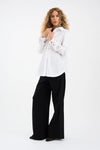 Woman wearing a white blouse and black pants on a white background from Pieszak