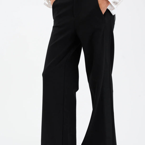 Person wearing black wide-leg pants and a white shirt on a white background from Pieszak