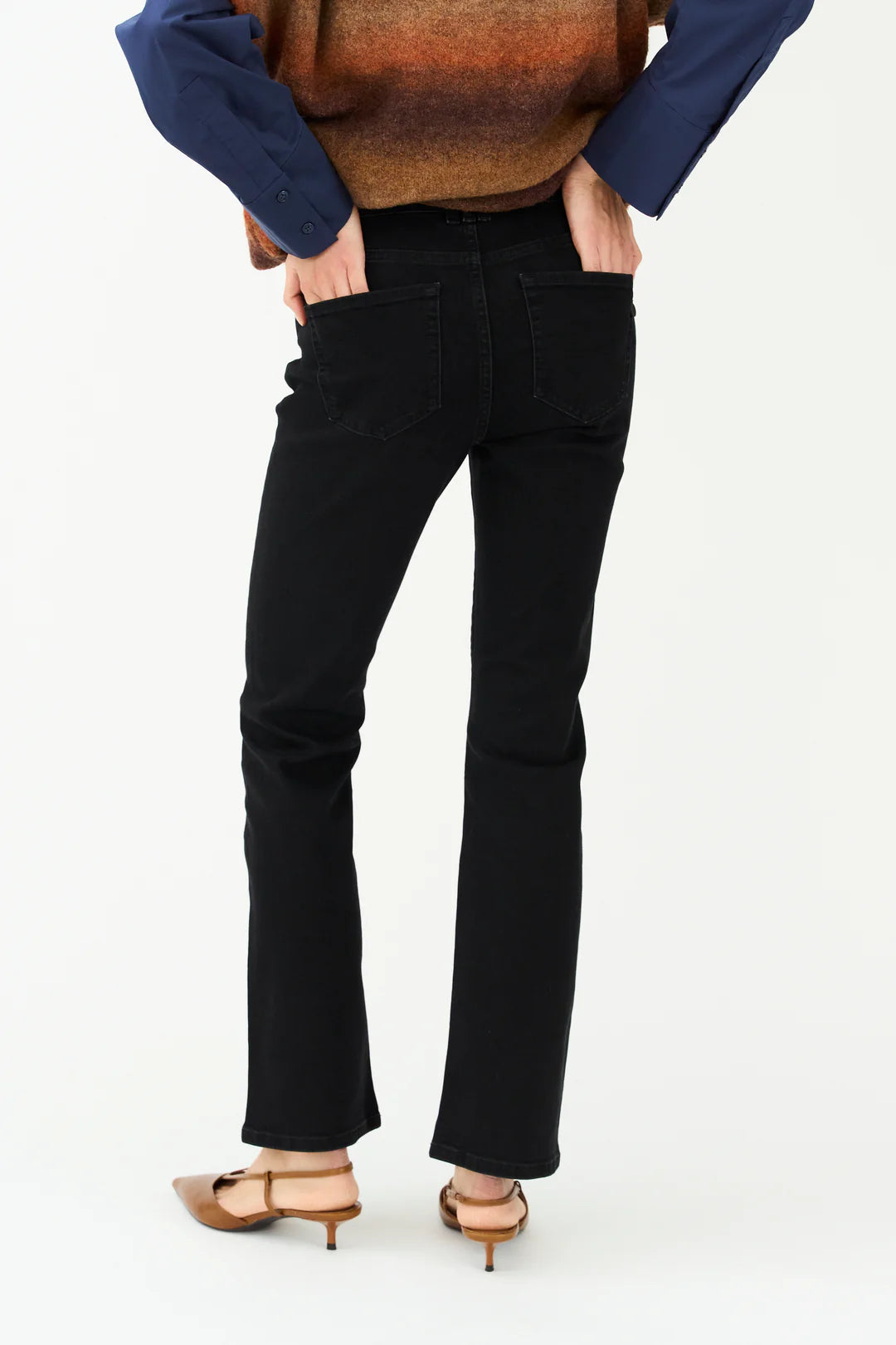 Person wearing black pants and a blue top on a white background