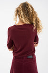 Person wearing a burgundy sweater and pants on a white background rear view