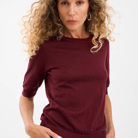 Woman wearing a burgundy outfit against a white background from Piezsak