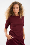 Woman wearing a burgundy outfit against a white background from Piezsak