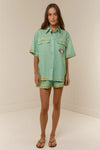 short sleeve light green oversized linen shirt with button flap pockets and crab on pockets from palm noosa model shot