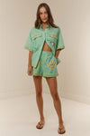 short sleeve light green oversized linen shirt with button flap pockets and crab on pockets from palm noosa model shot