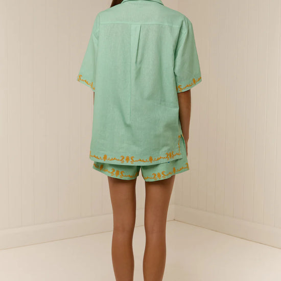 short sleeve light green oversized linen shirt with button flap pockets and crab on pockets from palm noosa rear