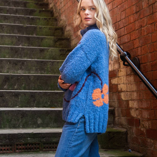 blue roll neck with ribbed cuffs, hem and neck with colourful floral design side view 