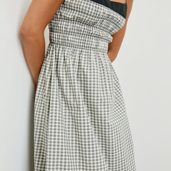 Person wearing a black and white checkered dress against a plain background