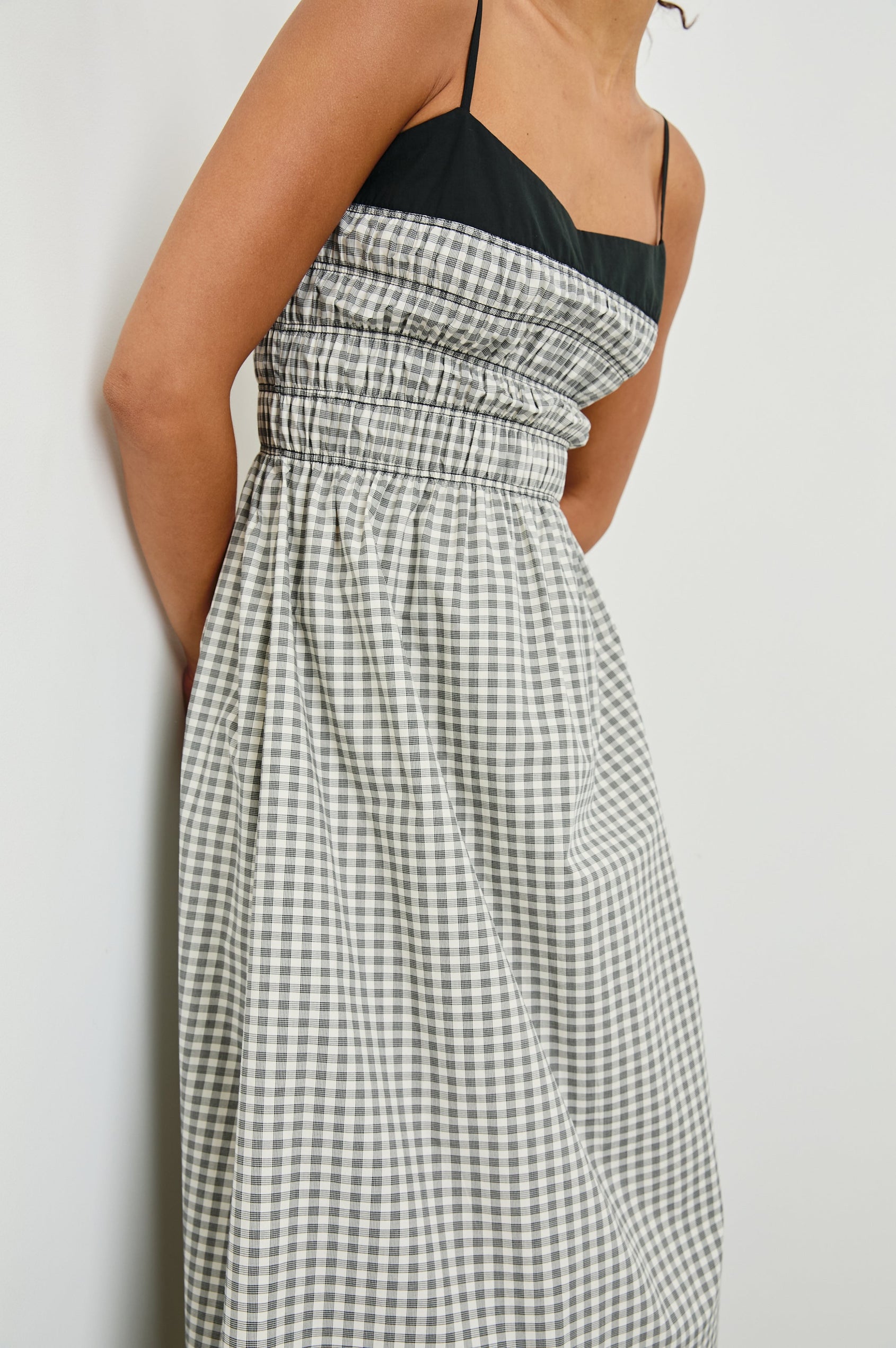 Person wearing a black and white checkered dress against a plain background