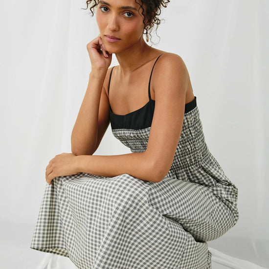 Woman wearing a checkered dress sitting on a white background
