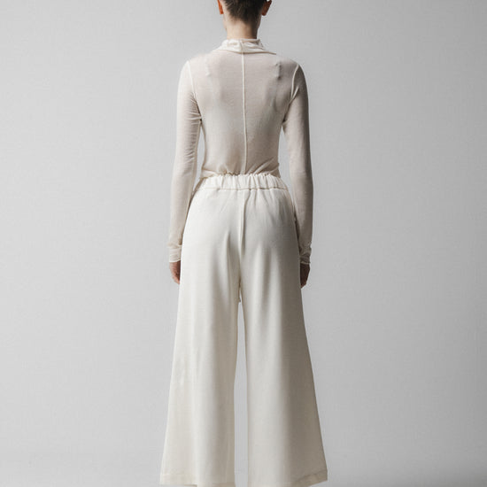 Person wearing a white outfit with wide-leg pants on a plain background  from Emin + Paul