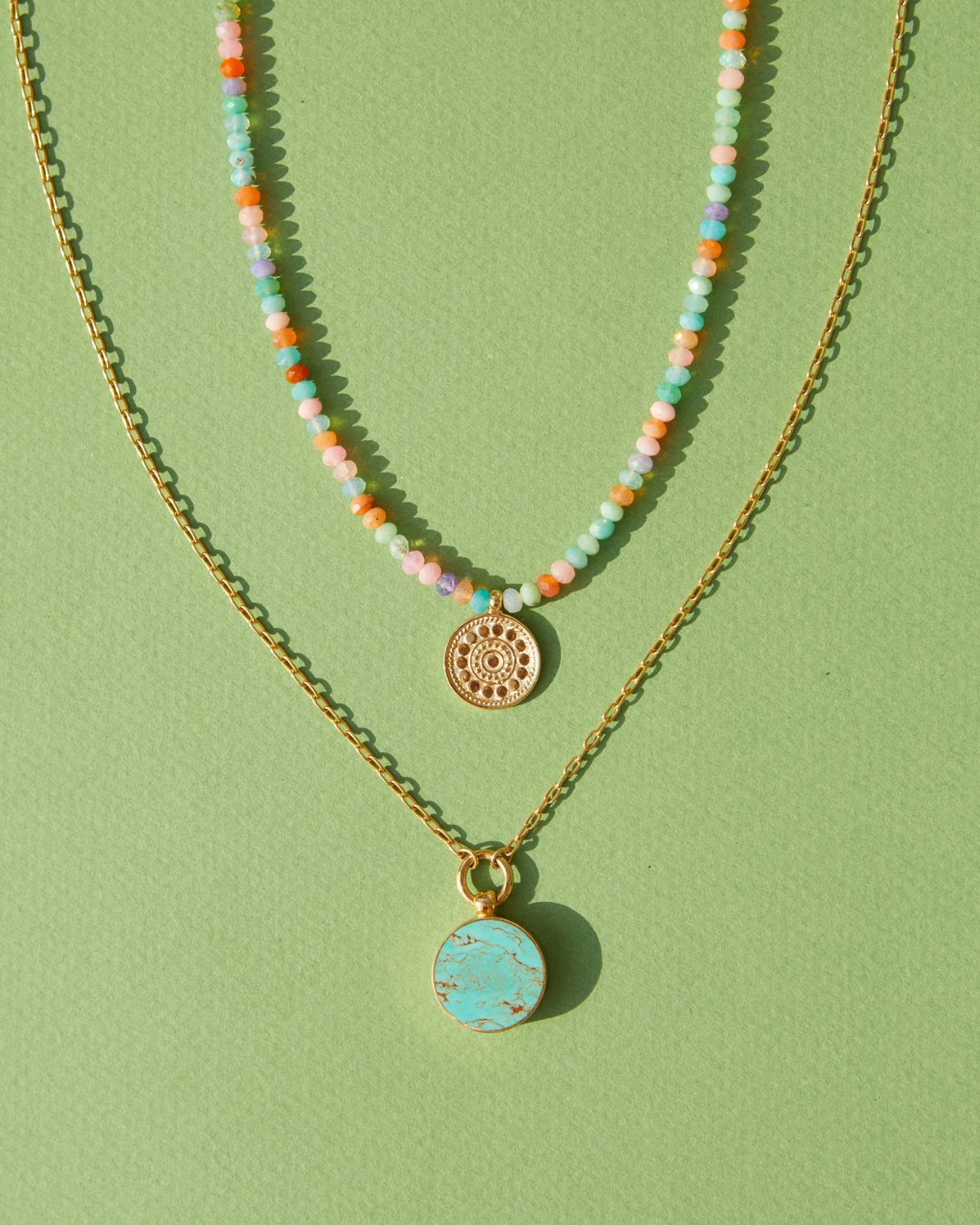 Two Anna Beck Necklaces on a green background