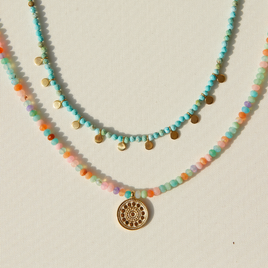 Two beaded necklaces with a gold pendant by Anna Beck on a light background