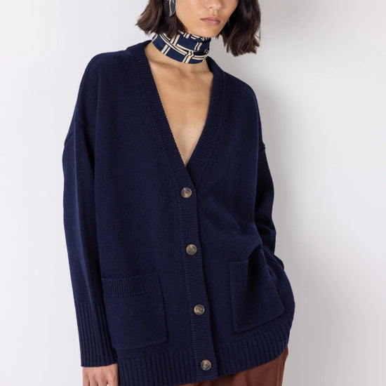 Woman wearing a navy blue cardigan over a brown outfit on a white background