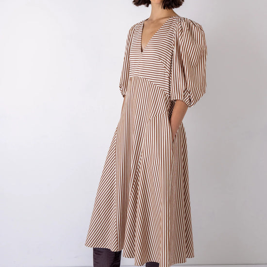 Woman wearing a striped dress with brown boots on a white background