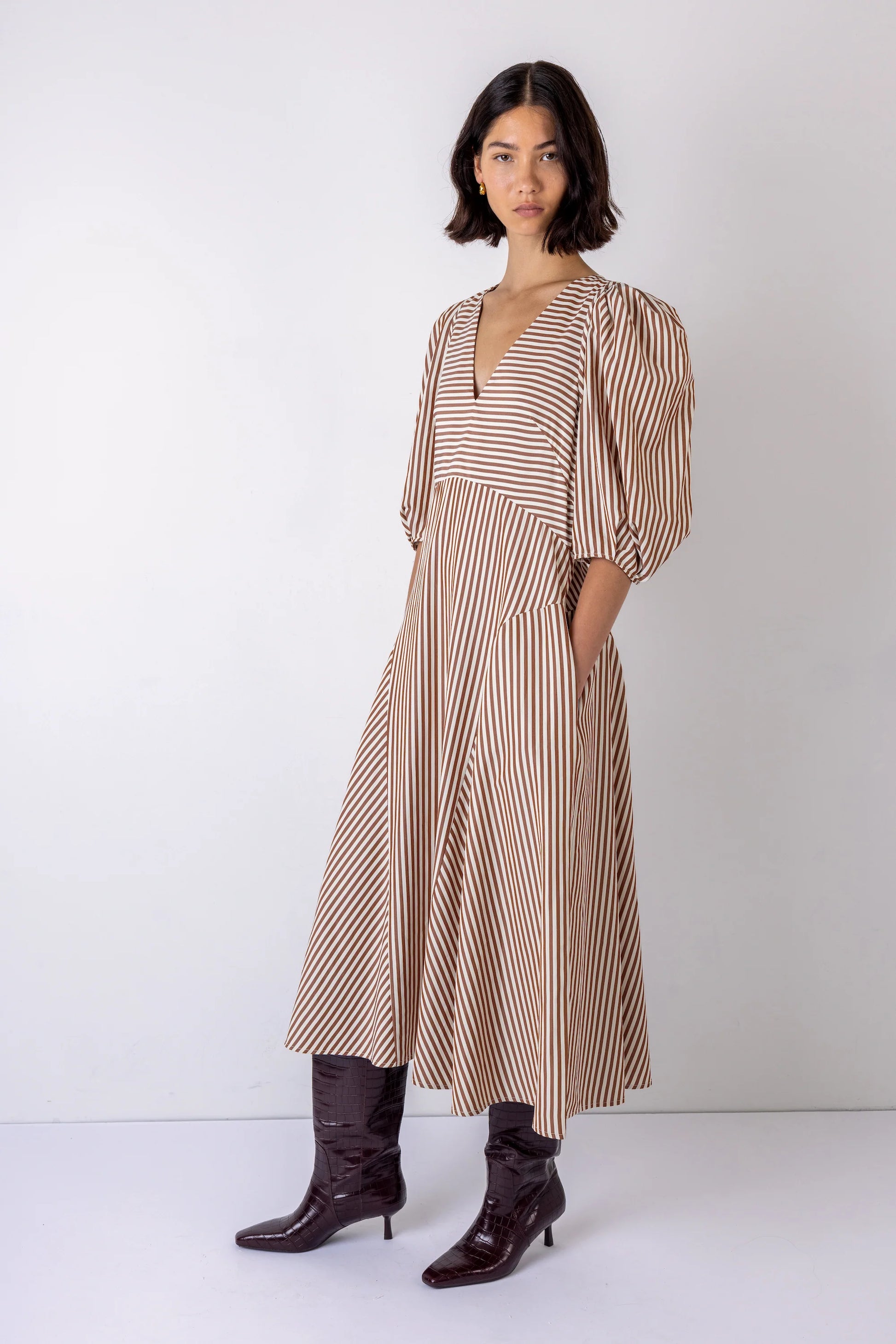 Woman wearing a striped dress with brown boots on a white background
