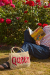 beige string bag with slogan on the grass