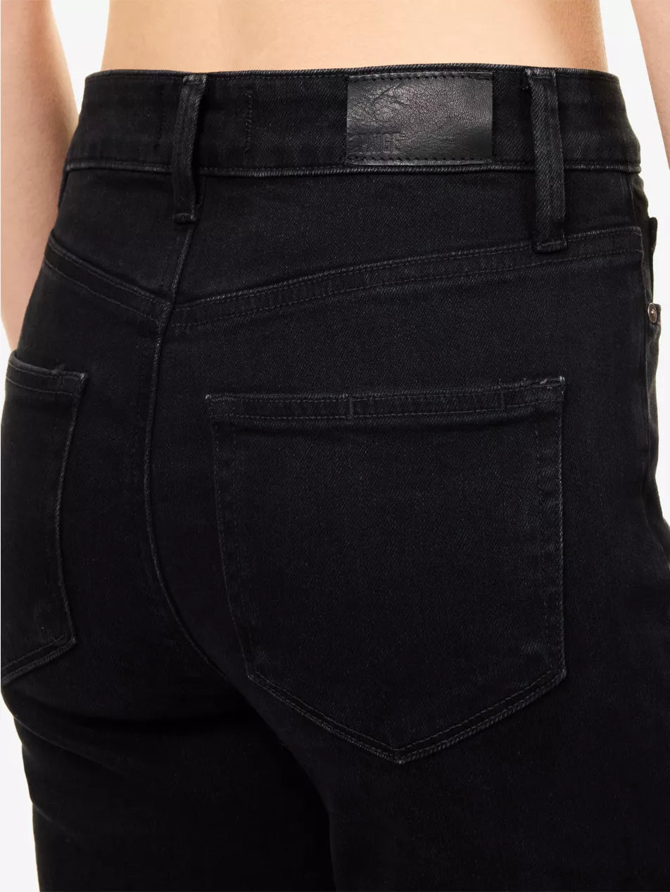 Close-up back view of a person wearing black denim jeans, showing the waistband, belt loops, and back pocket details.