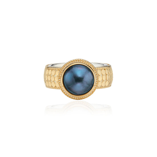 gold cocktail style ring with dot detailing and a blue pearl in the centre