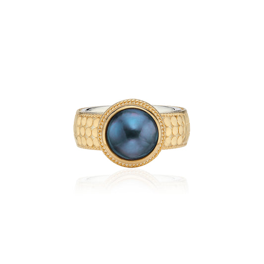 gold cocktail style ring with dot detailing and a blue pearl in the centre