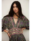 Woman wearing a patterned dress against a plain background