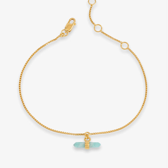 Gold bracelet with a blue stone on a white background