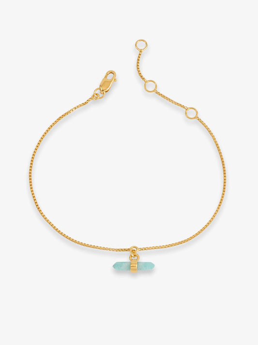 Gold bracelet with a blue stone on a white background