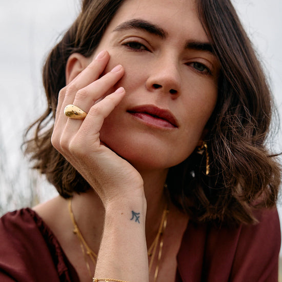 Rachel Jackson gold bird bracelet worn by a woman with other jewellery 