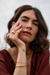 Rachel Jackson gold bird bracelet worn by a woman with other jewellery 
