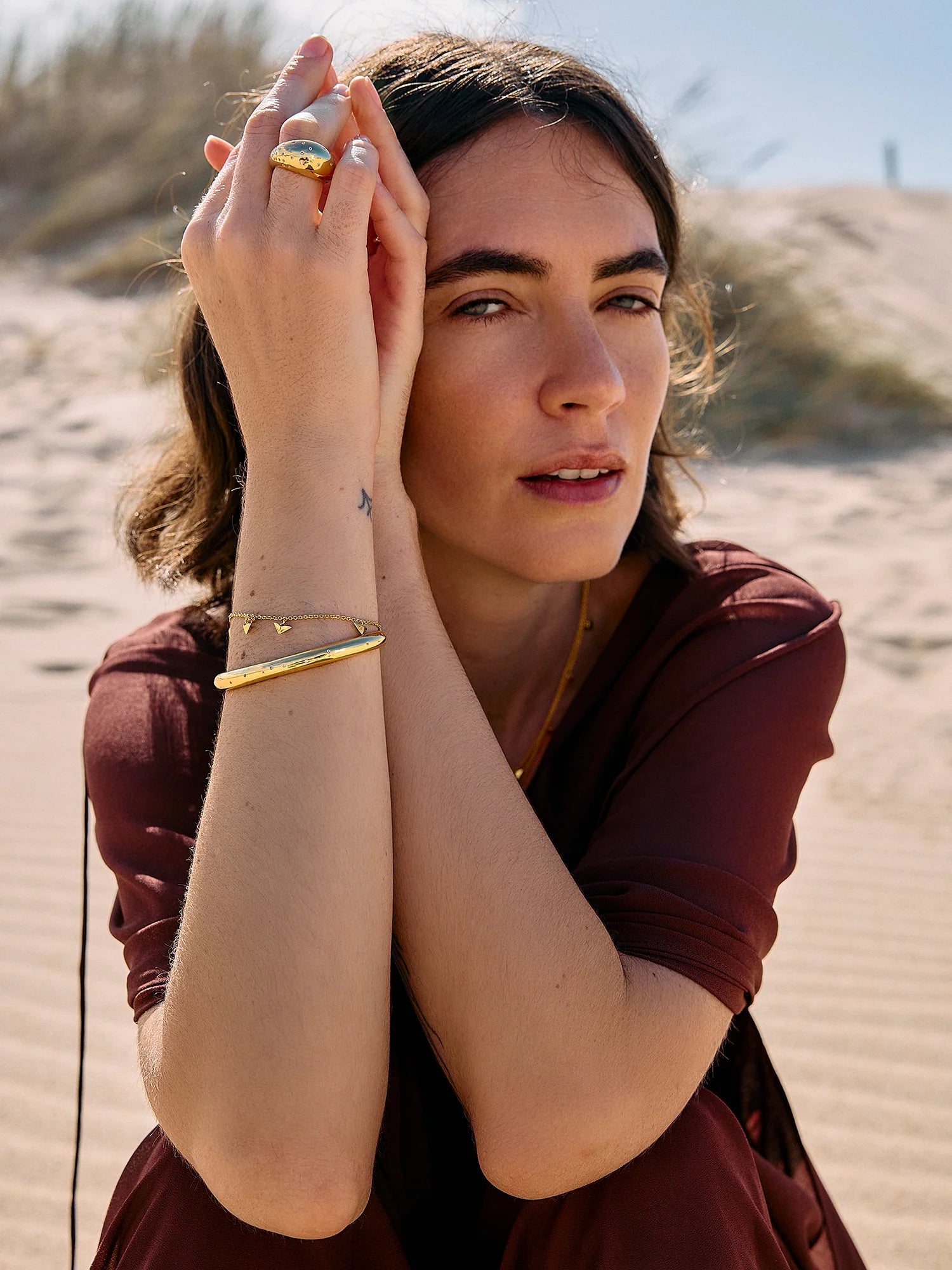Rachel Jackson gold bird bracelet worn by a woman on the beach