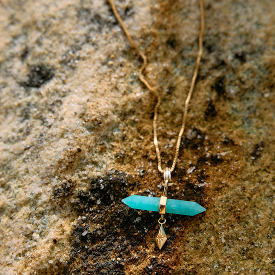 Necklace with a turquoise pendant on a textured stone surface