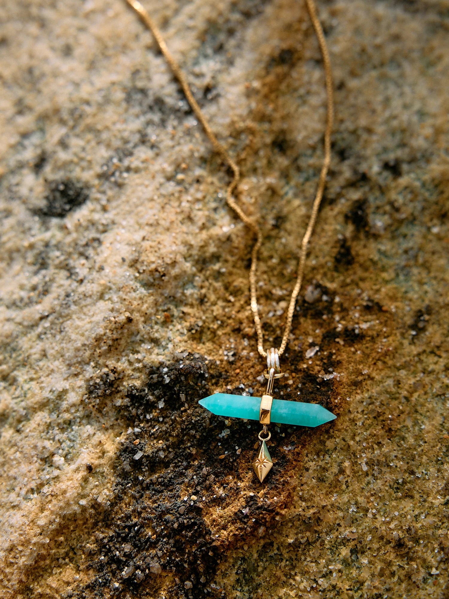 Necklace with a turquoise pendant on a textured stone surface