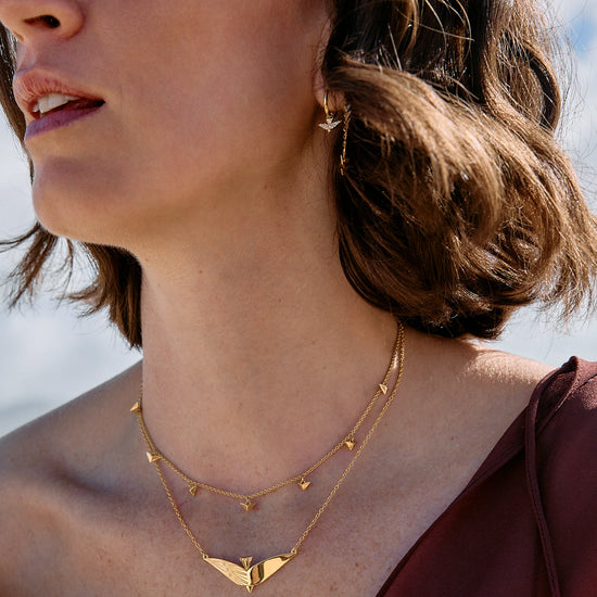 Woman wearing a gold necklace with a blurred natural background
