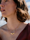 Woman wearing a gold necklace with a blurred natural background